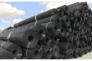 Multiple dark geogrid rolls stacked in a storage area.