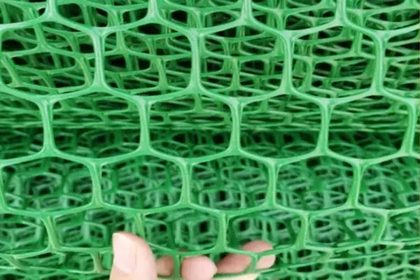 Hand holding a green interlocking cellular paving panel.